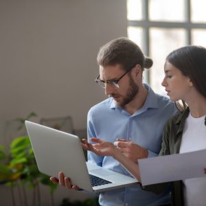 Girl and man with laptop discussing work plan.